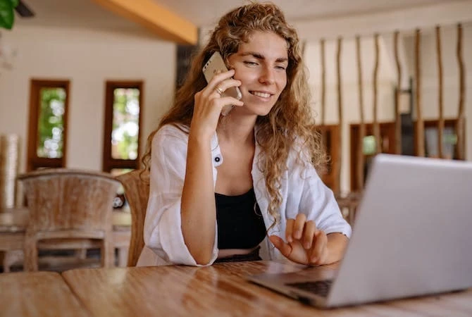 Telefonierende Frau an Laptop